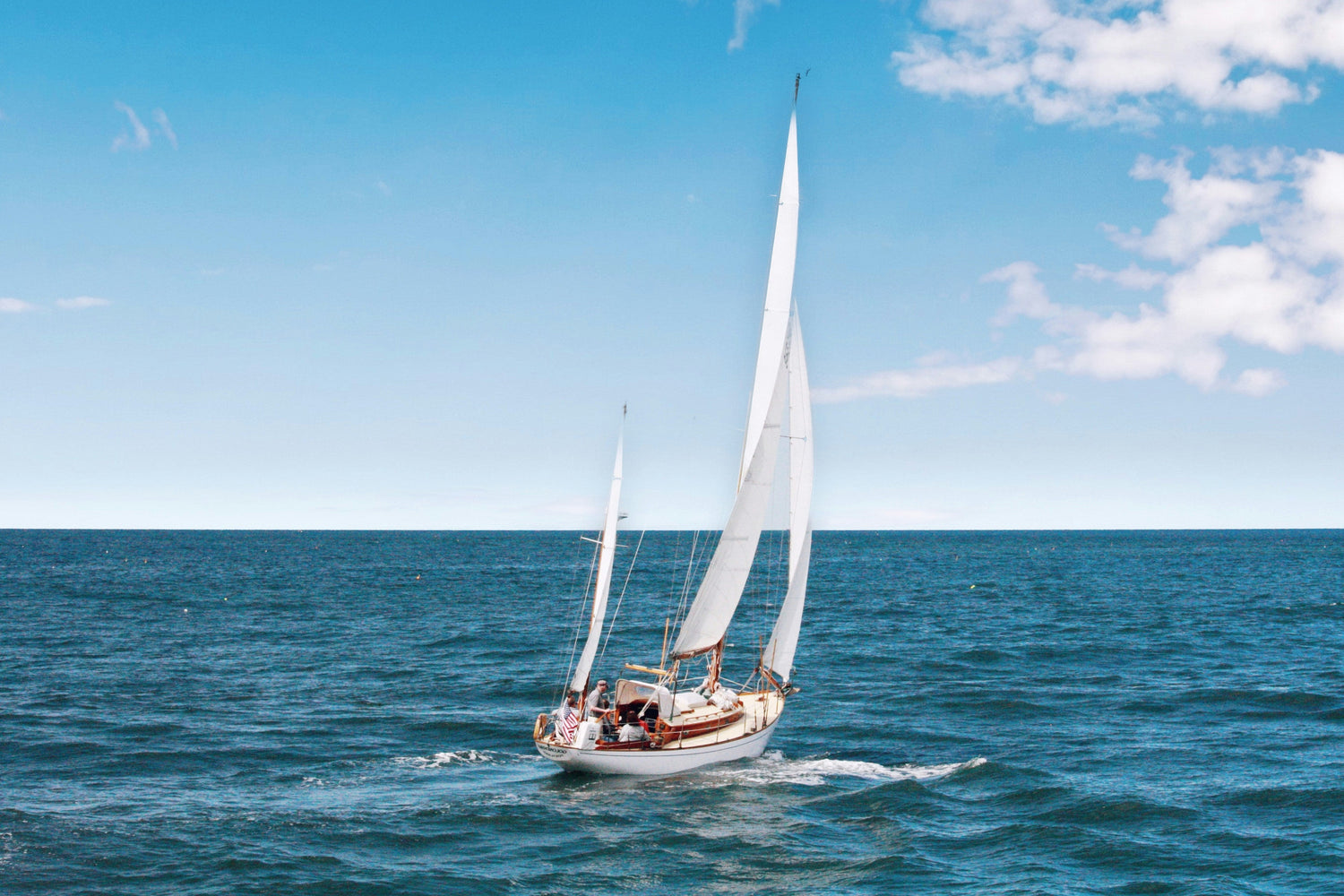 Sailboat with white sails on a blue ocean under a clear sky